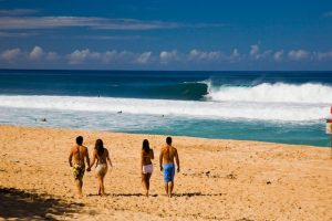 Couples watching surfers off a North Shore beach