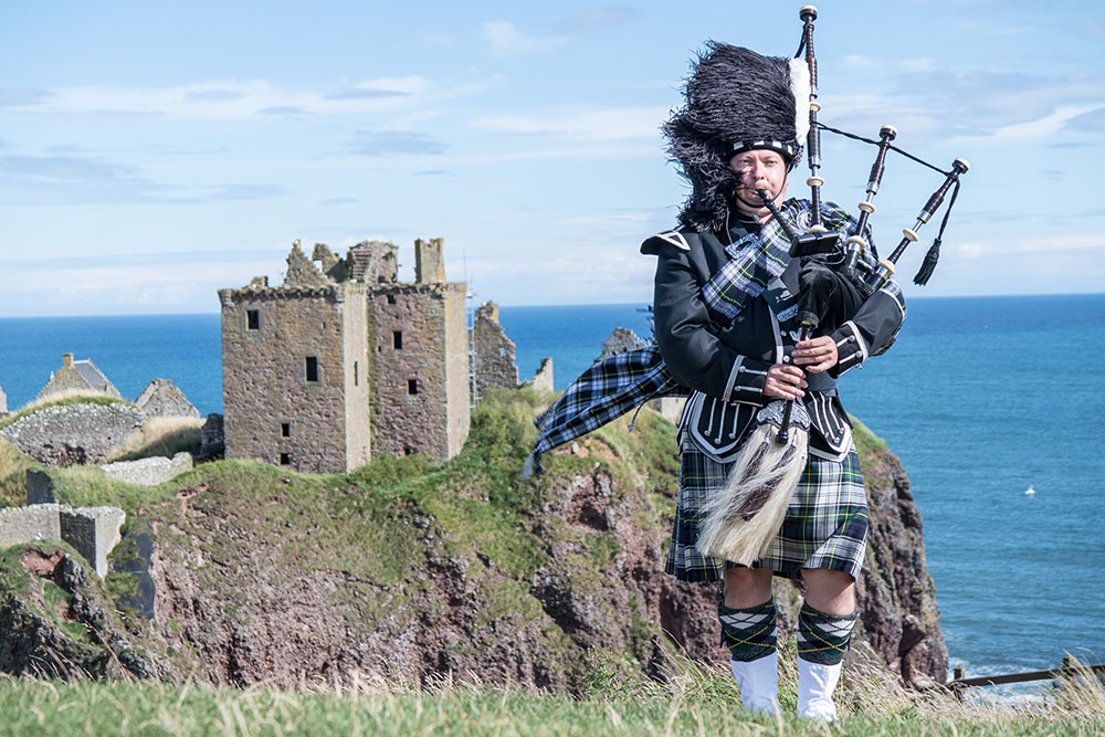 Traditional Scottish bagpiper at Dunnottar Castle