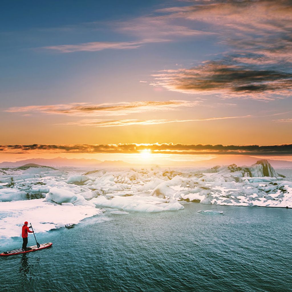 Landscaped, Beautiful glacier lagoon in sunset with a guy paddle boarding