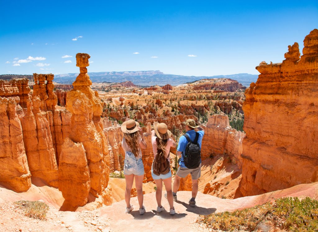 Family standing next to Thor's Hammer hoodoo on top of mountain looking at beautiful view. Bryce Canyon National Park, Utah, USA