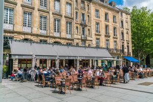Bordeaux, France, 9 may 2019 - Locals and tourists eating and drinking on a terrace on the 'Place Pey Berland' opposite of the Famous Cathédrale Saint-André de Bordeaux