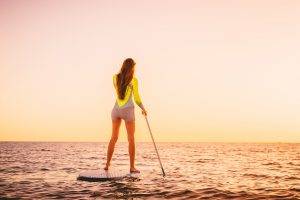 woman on stand up paddle board with beautiful sunset