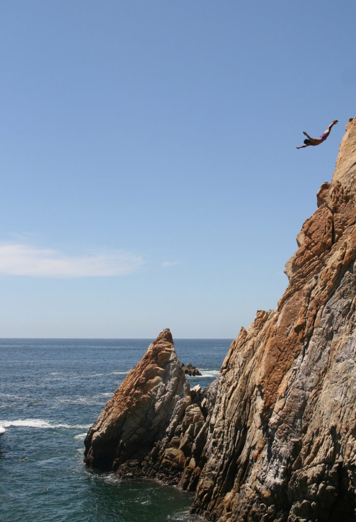 Photo of cliff diver at La Quebrada in Acapulco Mexico. Divers perform day and night for tourists risking their lives. Dives must be timed so that waves fill the lagoon with water