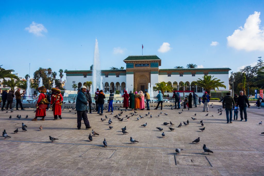 Moroccan water seller in traditional dress, and people walking around the Palace of Justice on Mohammed V Square in Casablanca