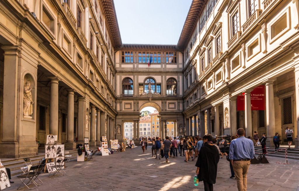 Tourists browsing through The Uffizi Gallery Museum in Florence, and walking toward the Arno river.