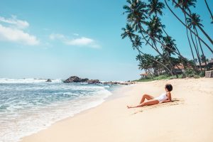Woman takes sunbath on tropical beach. Island paradise