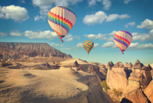 Hot air balloon flying over rock landscape at Cappadocia Turkey.