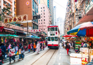 A Hong Kong tram squeezes past shoppers and stalls at the Chun Yueng Street Market in North Point, Hong Kong