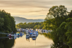 Scenic sunset view of Balloch harbour near Loch Lomond with floating boats reflected in river Leven, Scotland