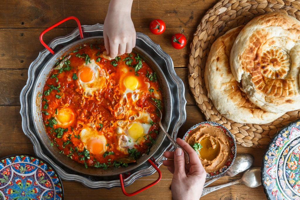 Tasty family breakfast with shakshuka, bread and hummus.