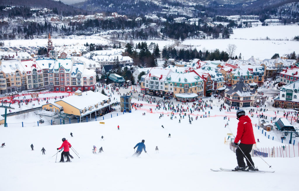Skiers and snowboarders are sliding down the main slope at Mont-Tremblant. Mont-Tremblant Ski Resort is acknowledged by most industry experts as being the best ski resort in Eastern North America.