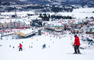 Skiers and snowboarders are sliding down the main slope at Mont-Tremblant. Mont-Tremblant Ski Resort is acknowledged by most industry experts as being the best ski resort in Eastern North America.
