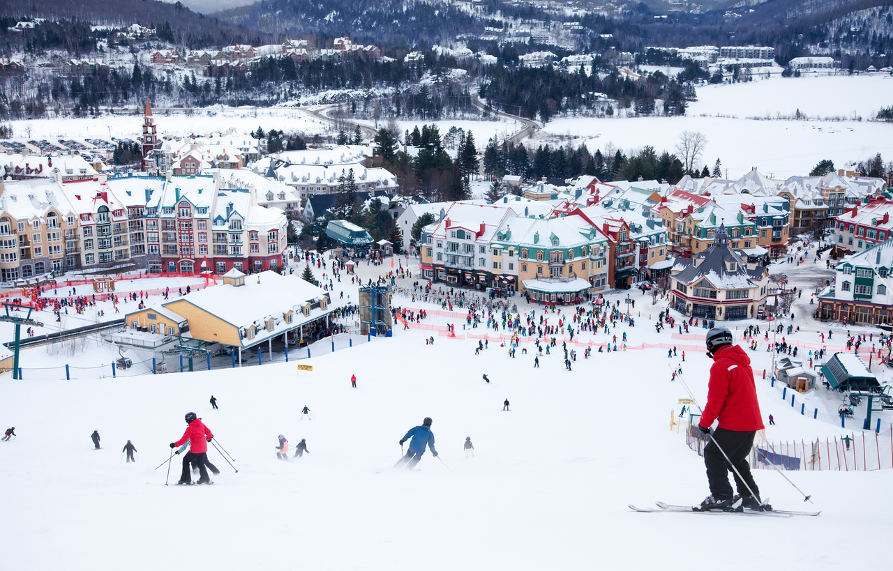 Skiers and snowboarders are sliding down the main slope at Mont-Tremblant. Mont-Tremblant Ski Resort is acknowledged by most industry experts as being the best ski resort in Eastern North America.