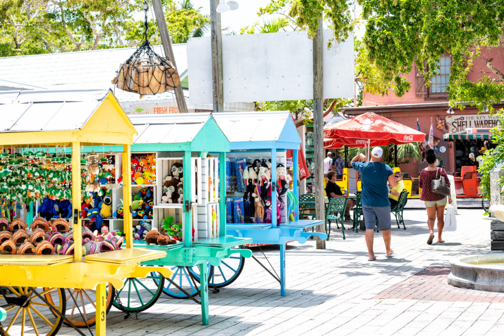 Duval street Mallory Square outdoor shopping mall, market, people walking, buying souvenirs, in summer Florida city, multicolored stands, booth, kiosk selling toys