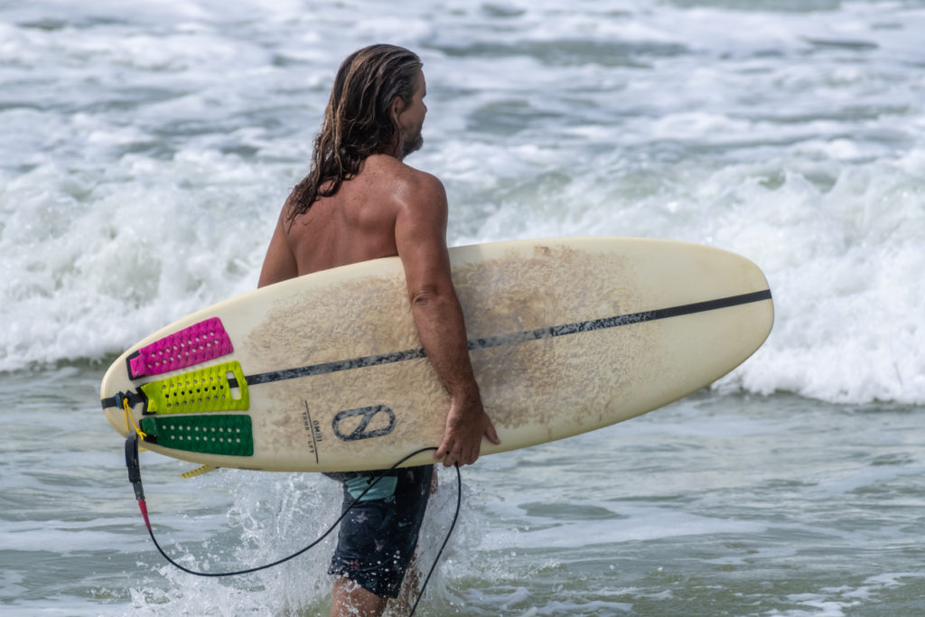 Panama City, Florida, USA. Surfer enters the water at St. Andrews State Park as Hurricane Barry churns in the Gulf of Mexico