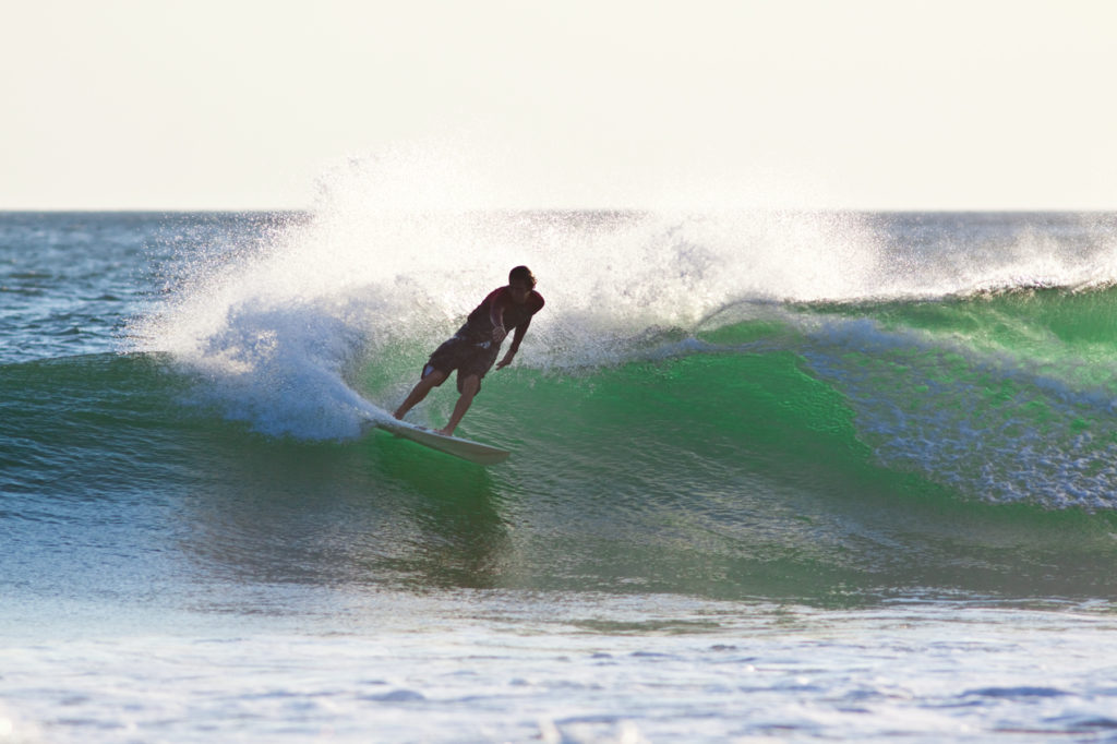 A surfer doing a cutback at sunset