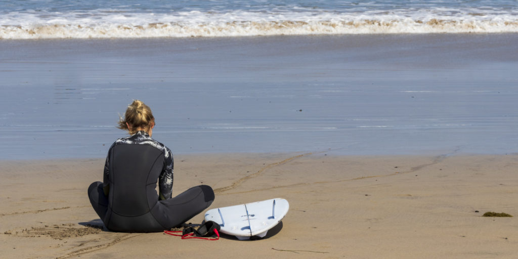 Surfer girl sitting at La Caleta beach. Lanzarote.