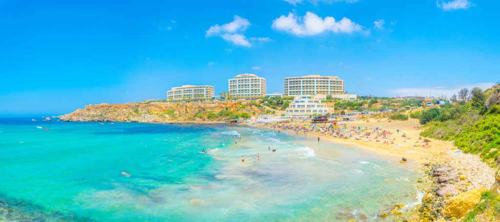 People are enjoying a sunny day at the Golden Bay beach on Malta