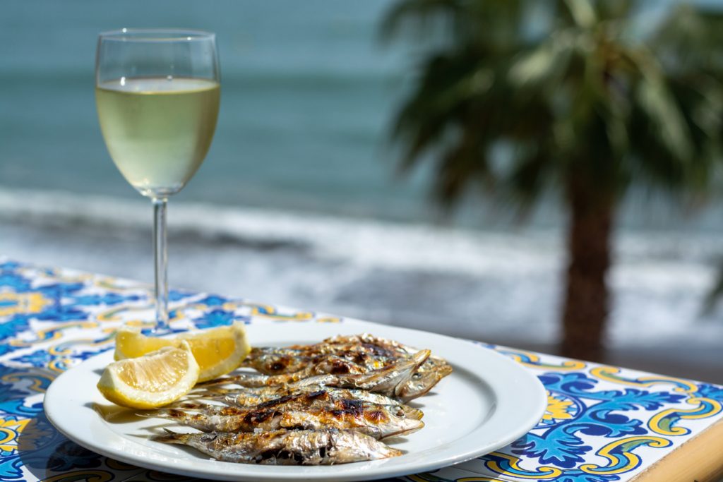 Sardines espeto, Marbella style fish on stick barbecue prepared on olive tree firewoods on beach served with white wine