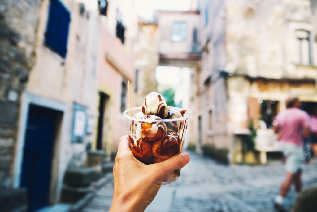 Tourist holds in hand Fritule (little doughnuts balls) with chocolate