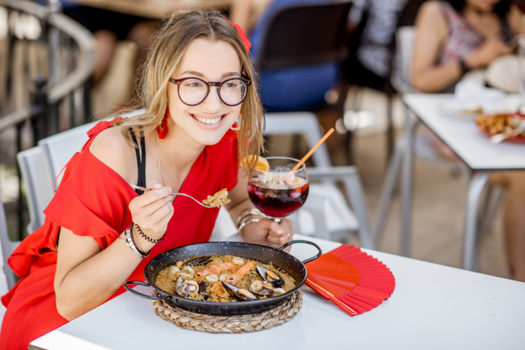 eating sea Paella, traditional Valencian rice dish, sitting outdoors at the restaurant in Valencia