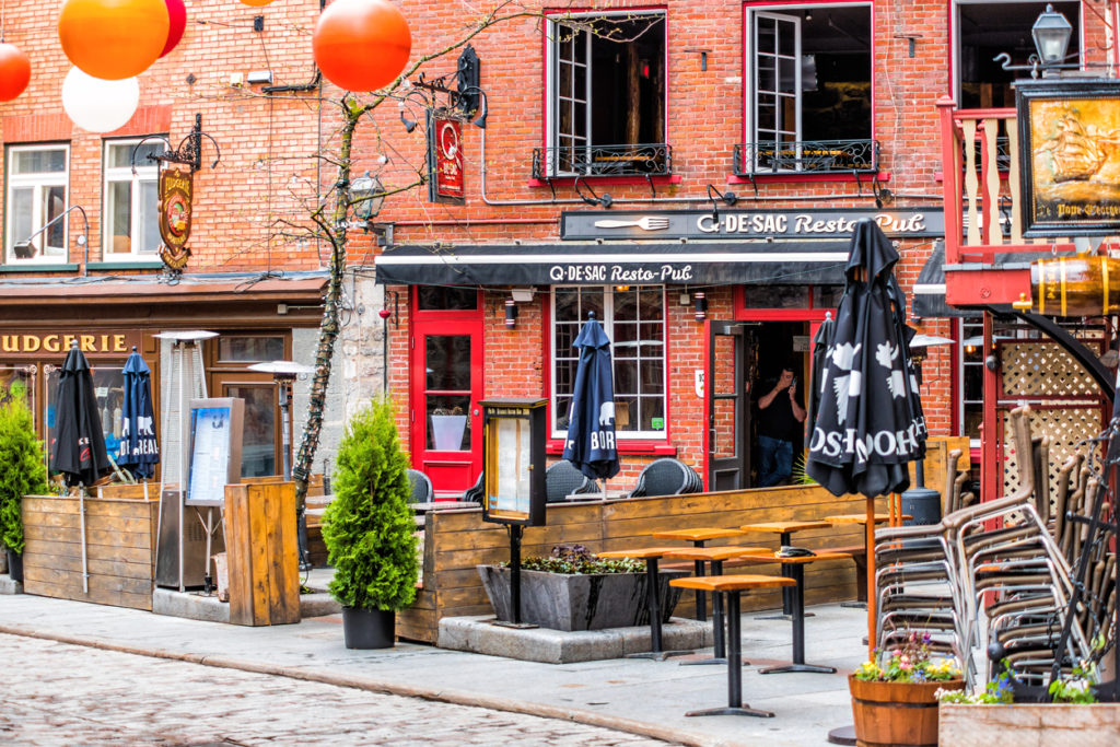 Lower old town cobblestone street called Sous le Fort with restaurants and hanging colorful decorations