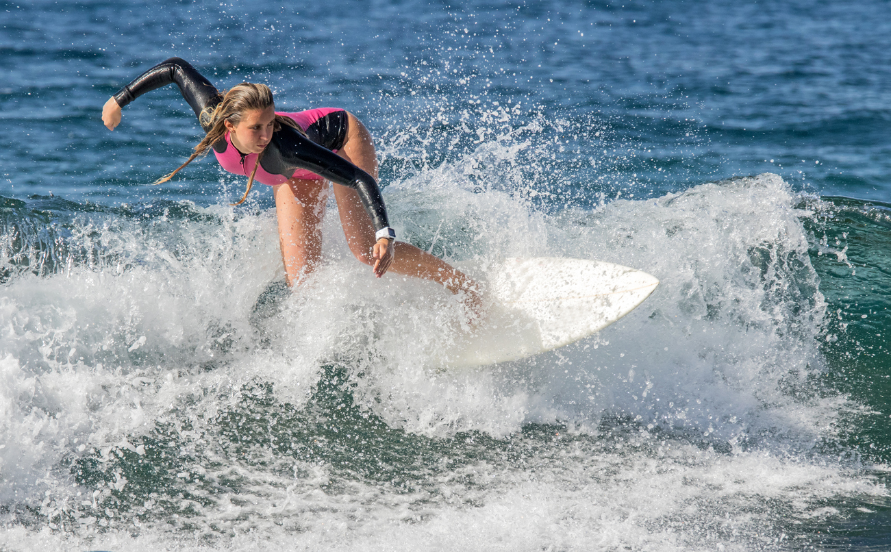 A female surfer rides a wave at the beach in Playa De Las Americas, Tenerife.