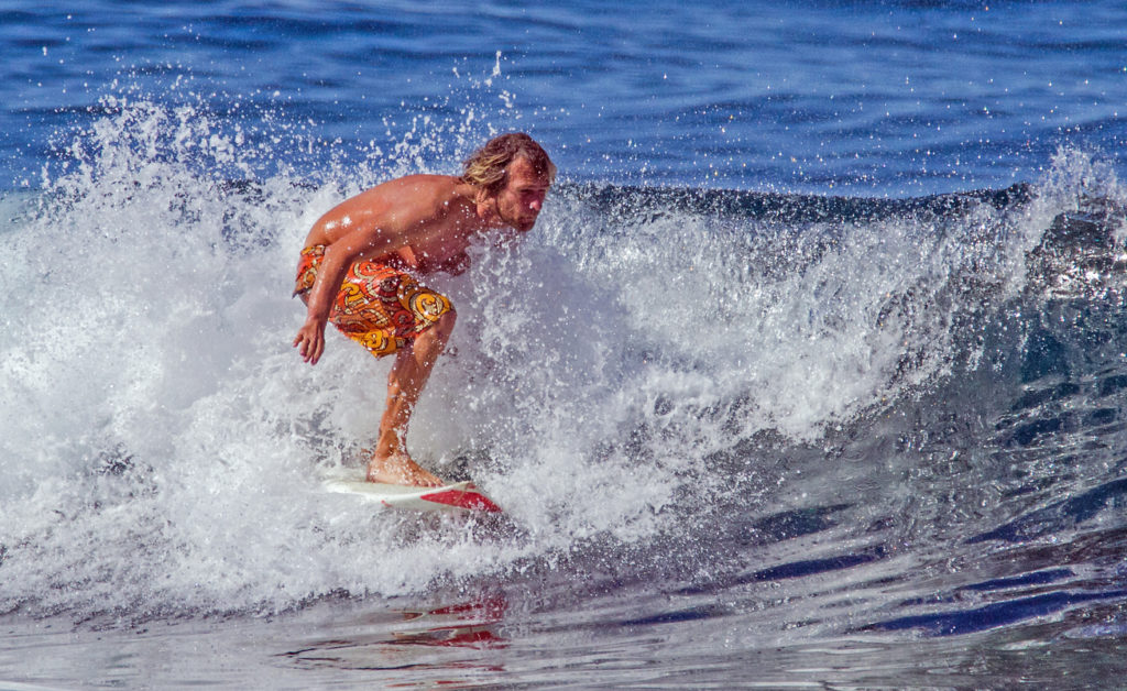 A surfer rides a wave at the beach in Playa De Las Americas, Tenerife.