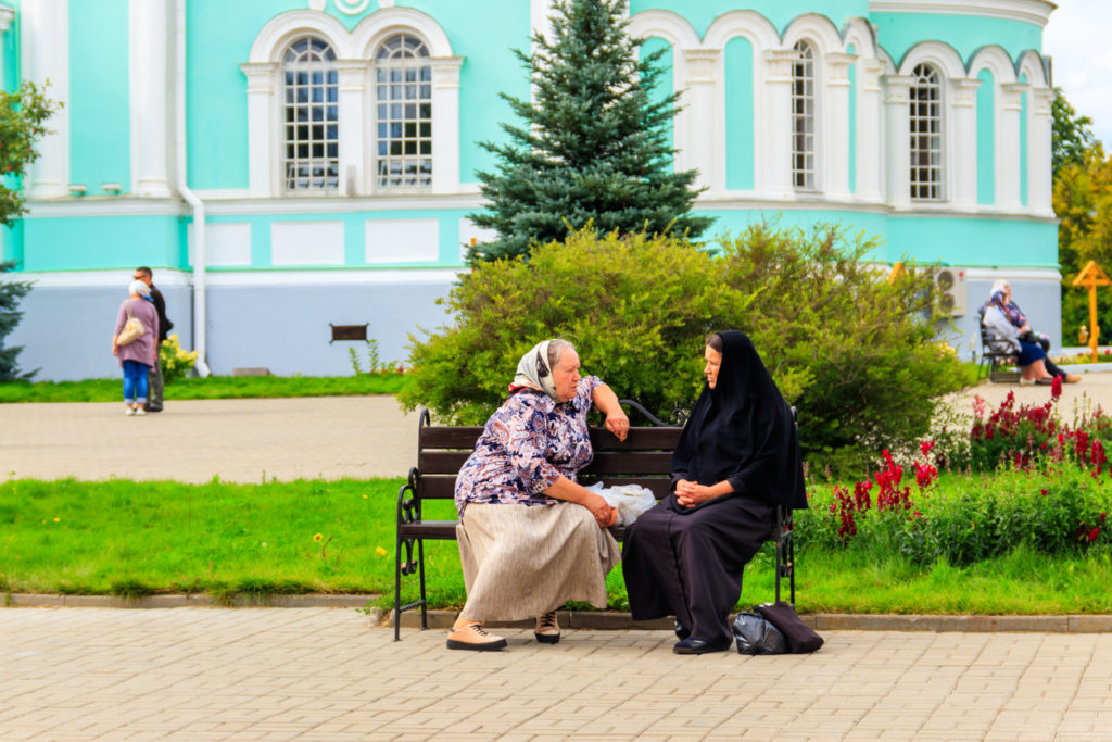 Orthodox nun and a pilgrim sitting on a bench