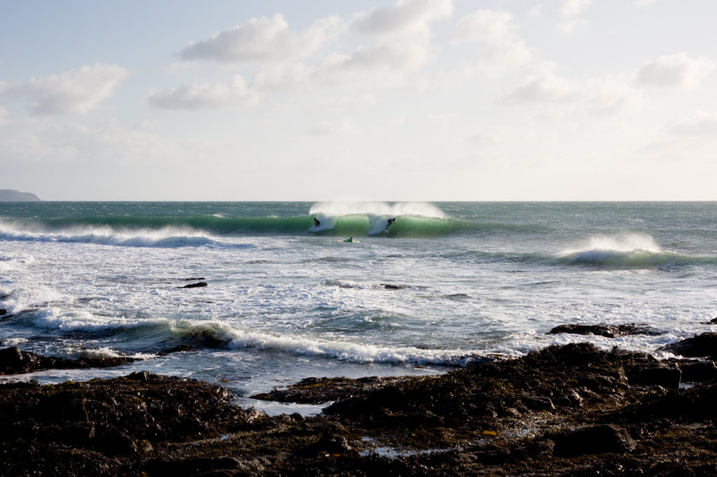 Surfers ride a wave at a reef in Porthleven