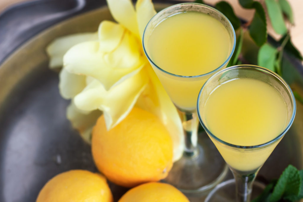 Limoncello in elegant liquor glasses with lemons, mint
