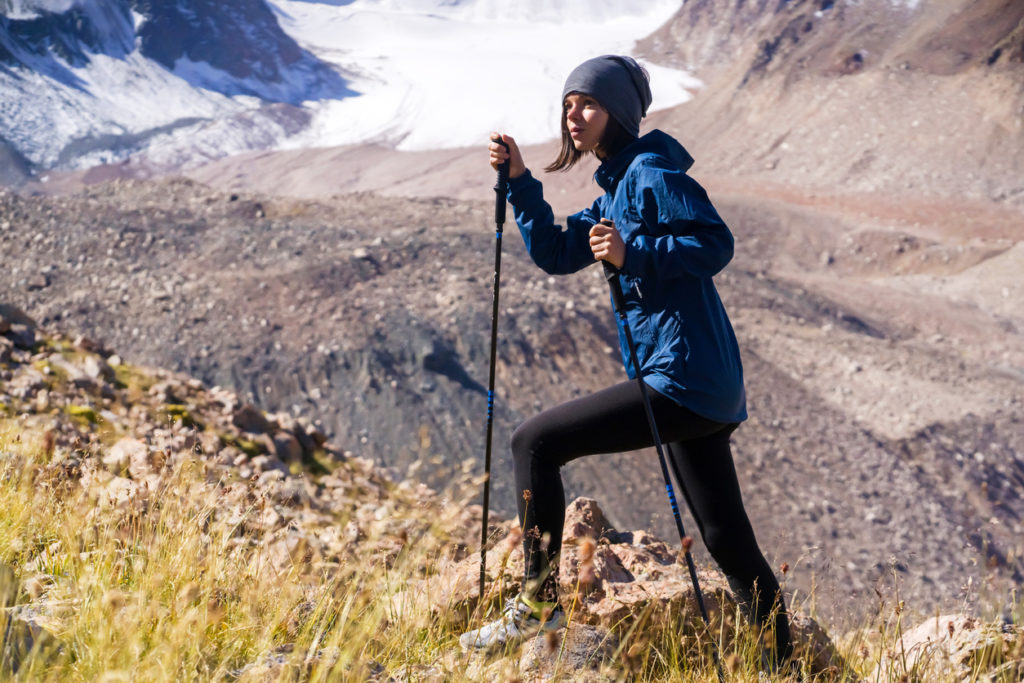 Female climbing trails in the mountains with glaciers in the distance.