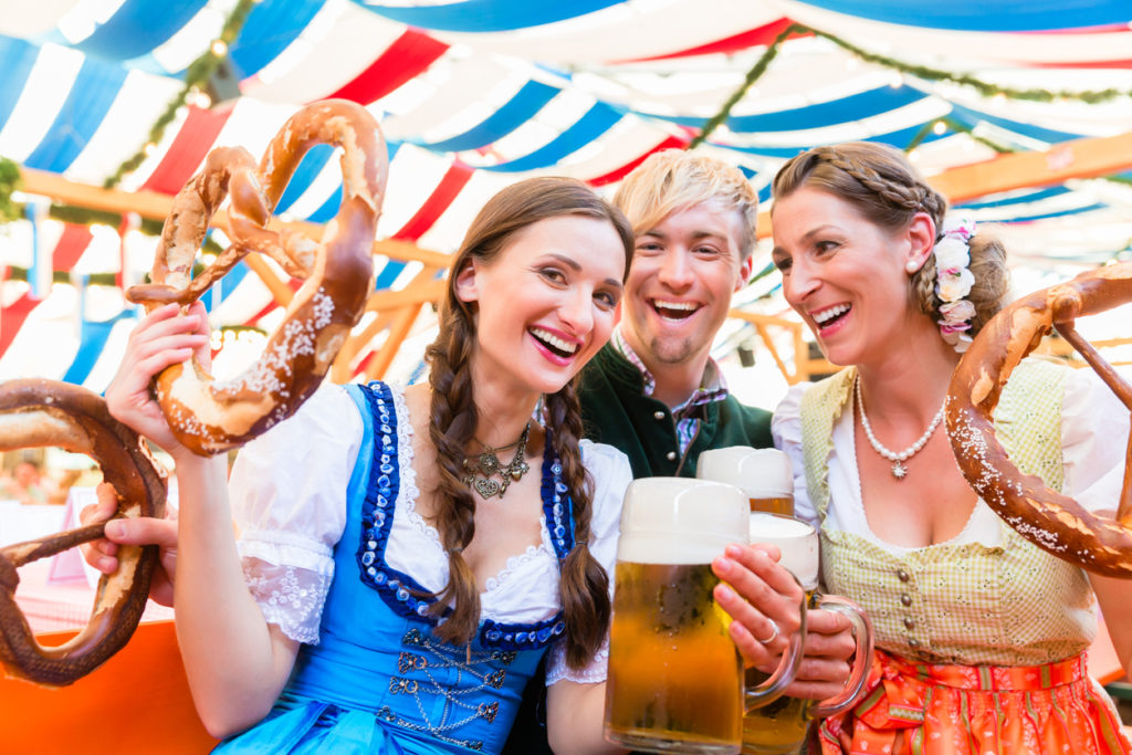 Friends with giant pretzels in Bavarian beer tent at Oktoberfest.