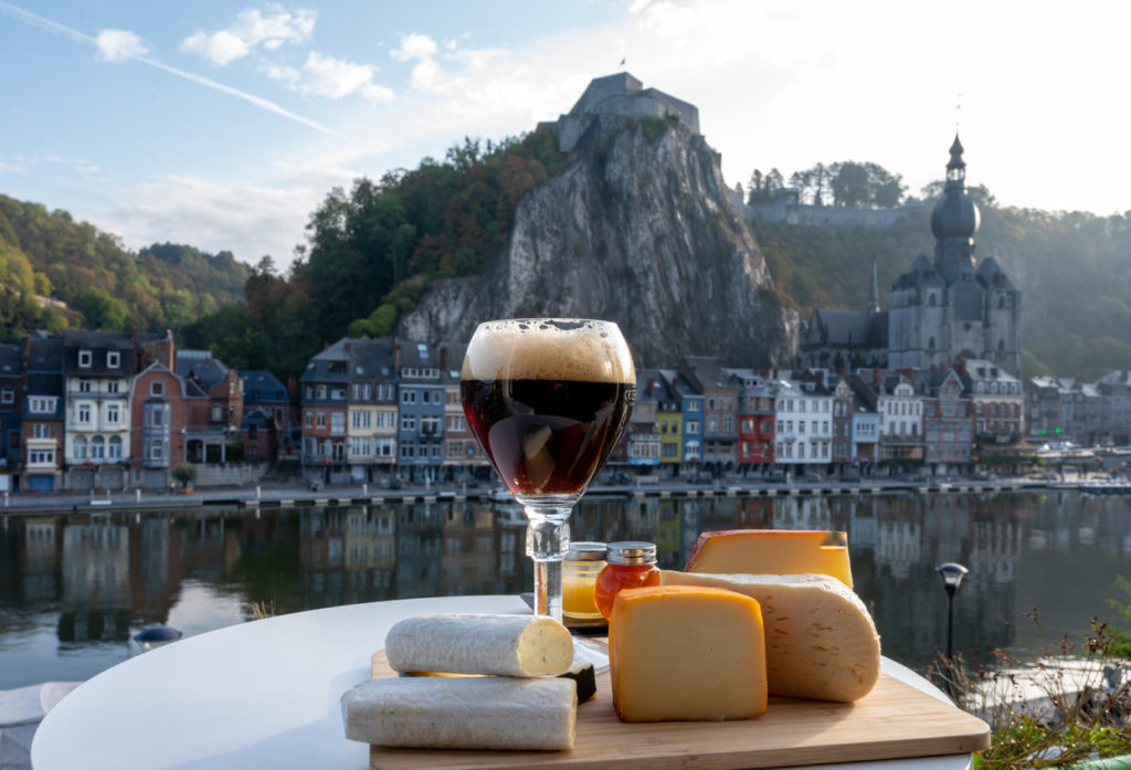 Glass of Belgian abbey beer and tasting of cheese with a view of the Maeuse river in Dinant, Belgium.