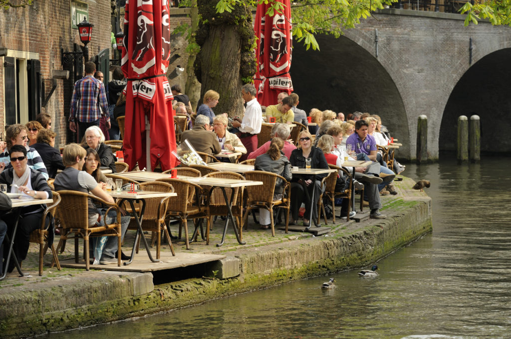 People enjoying food and drink at a restraunt on the wharf along the canal Oudegracht, Utrecht.