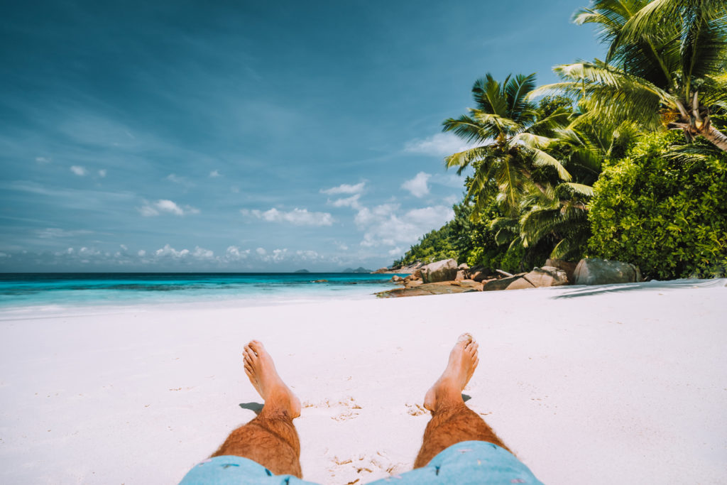 Man resting on a beautiful white beach.