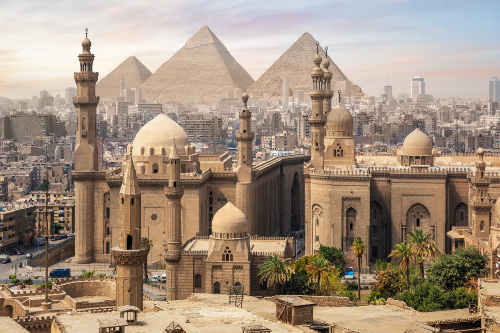 The Mosque of Sultan Hassan with the Great Pyramids of Giza and Cairo skyline.