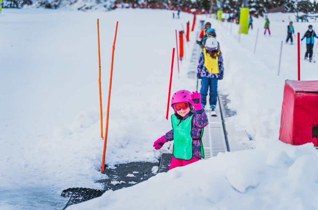 Young skier waving while going up on a ski conveyor in Andorra.