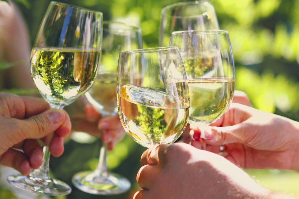 People holding glasses of white wine celebrating outside