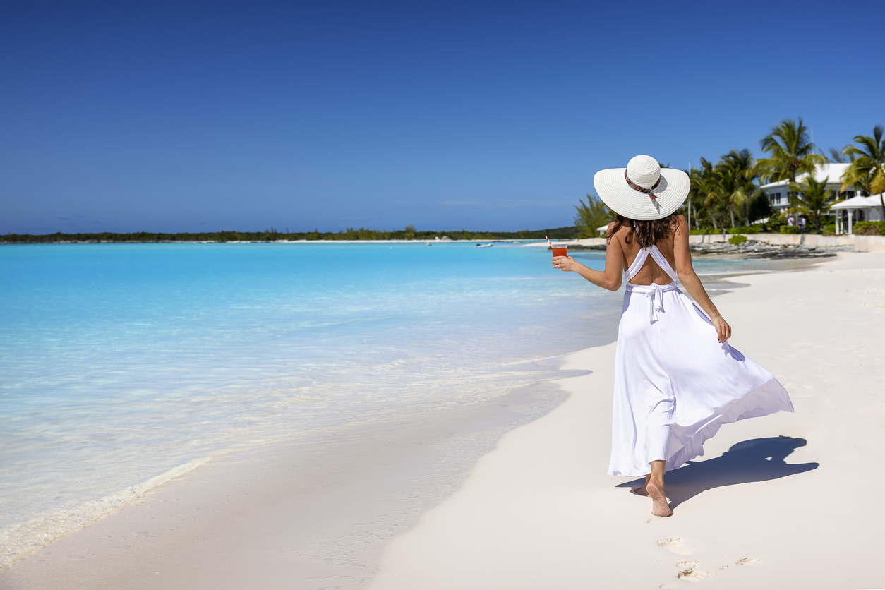 Lady walking along the sandy white beach in the Bahamas