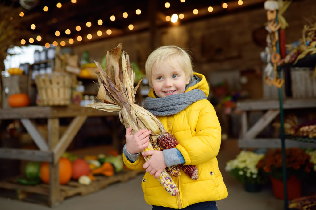 Little boy holding corn at the local market